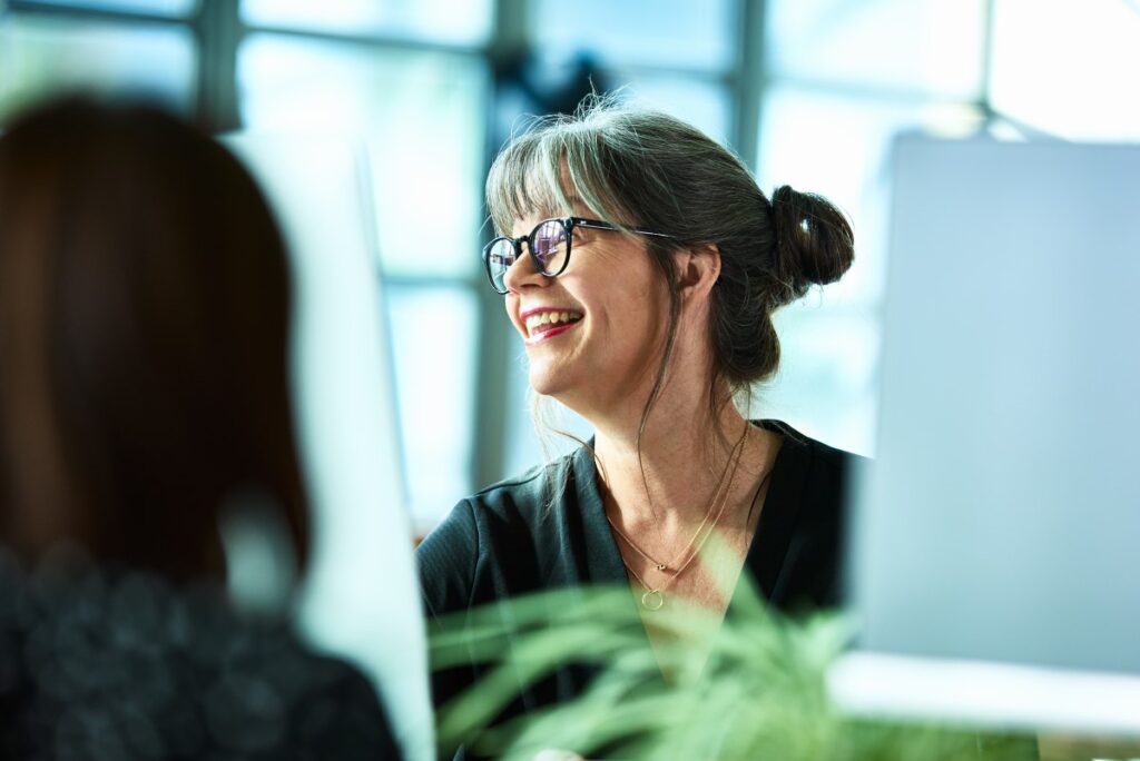 Female office worker smiling and looking away, with a cheerful and relaxed expression.