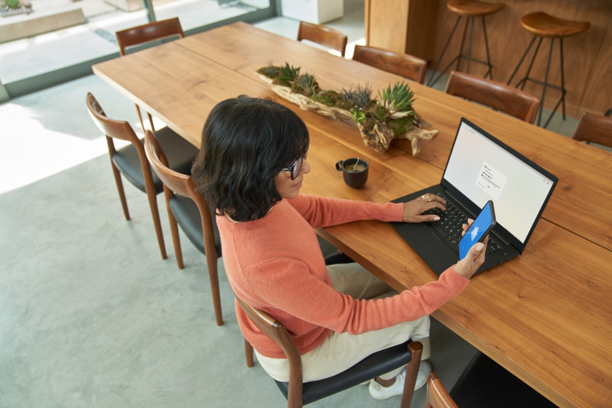 Business decision maker using mobile phone to complete multi-factor authentication to prepare to work from home