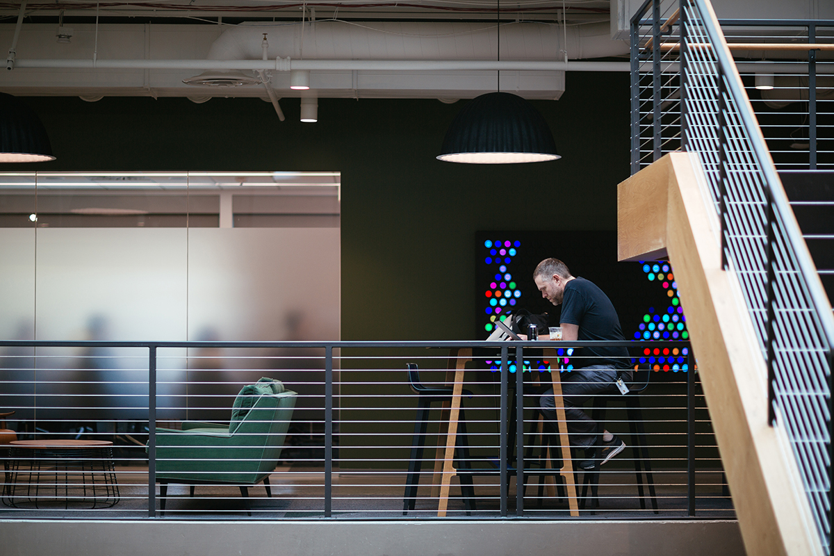 Photo of a man sitting alone at a table in an office building and works on a laptop