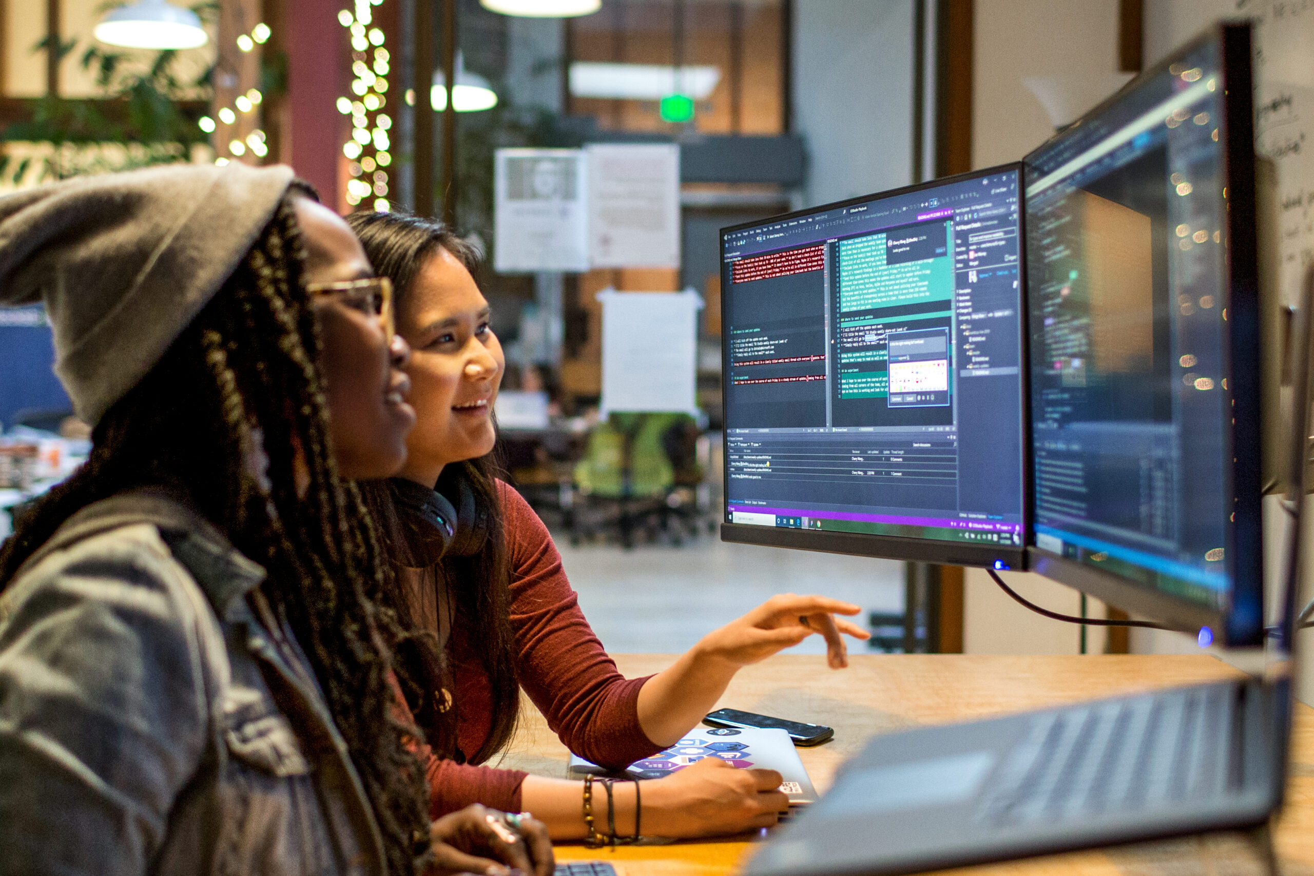 Two women in an office looking at a computer screen together and smiling
