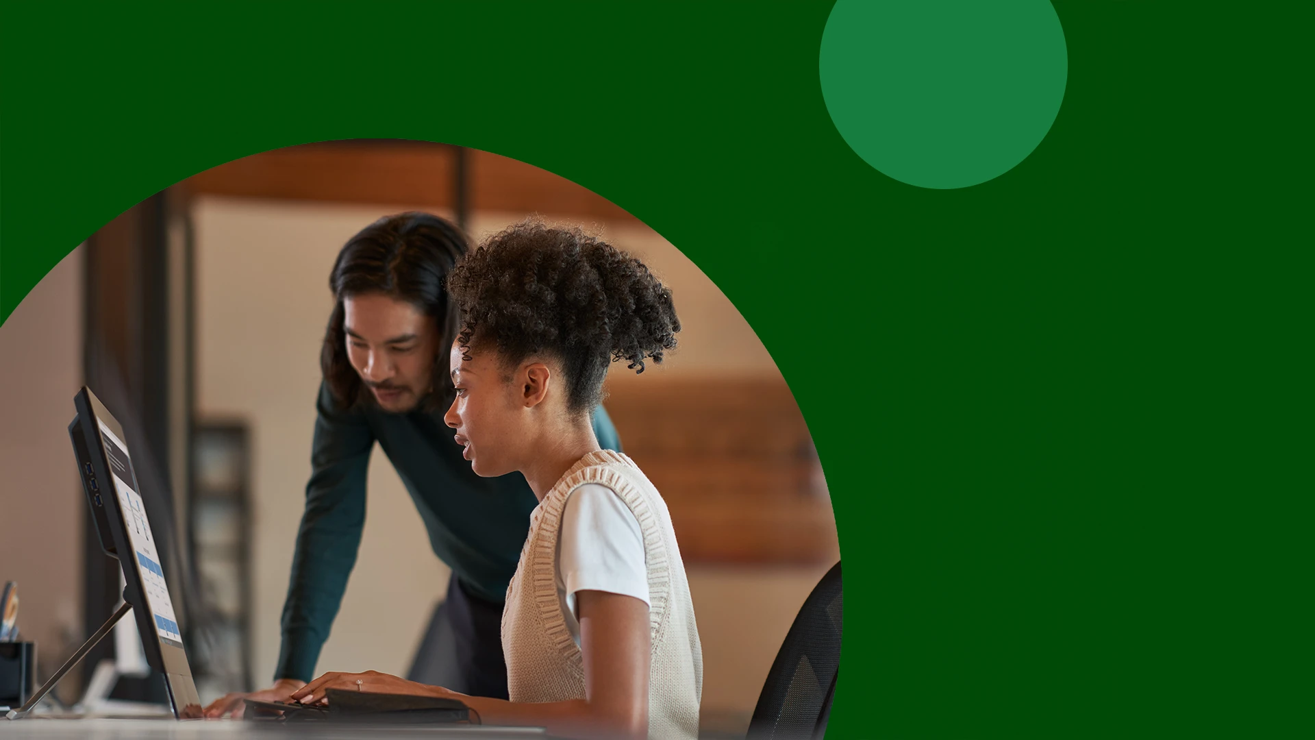 A man and a woman looking at a computer screen with a decorative, green frame around the image