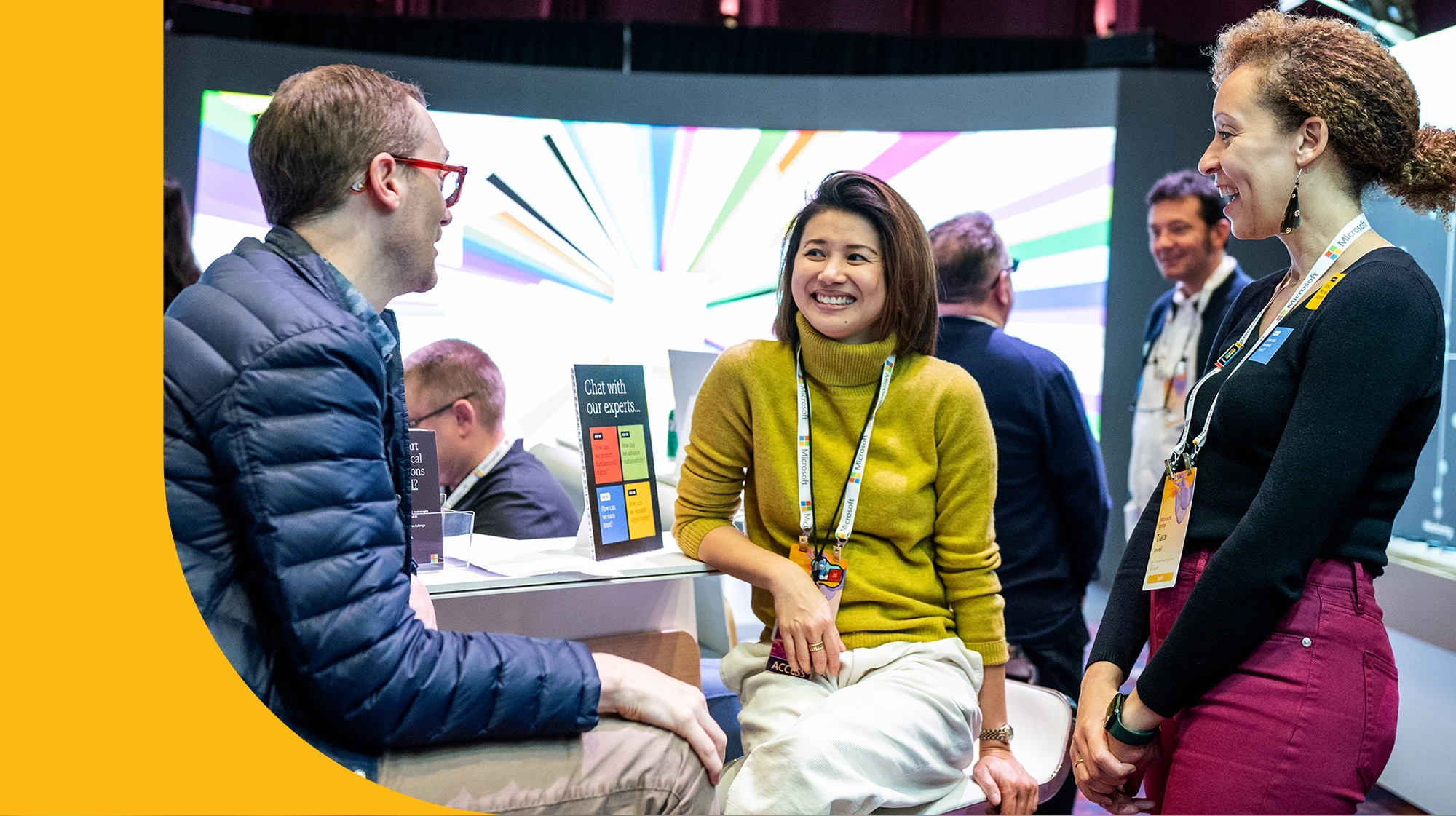 Three people sit and chat a demonstration booth at Microsoft Ignite