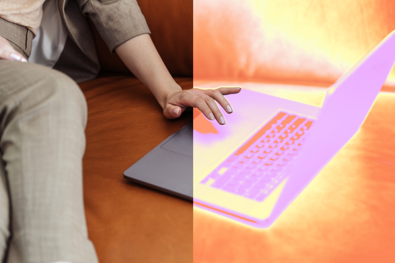 A person sitting on a couch touching a laptop