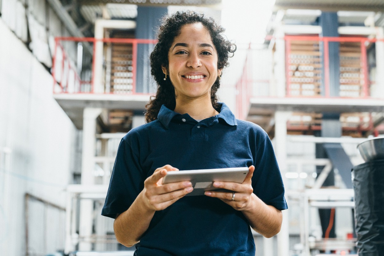 Woman, holding a tablet, working and smiling in a warehouse