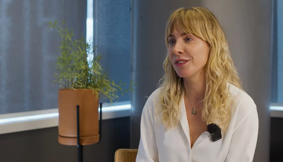 Lucia Rodrigues, Diretora de Habilidades em IA da Microsoft Brasil, sentada em ambiente interno com microfone.